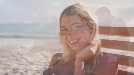 Animation-of-flag-of-united-states-of-america-over-happy-caucasian-woman-on-beach