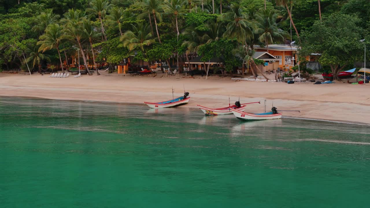 Scenic beach view of Haad Yuan with boats, palm trees, sandy shore, and lush jungle in Thailand. Calm turquoise water and tropical resort vibe. Perfect for travel, tourism, and lifestyle content.