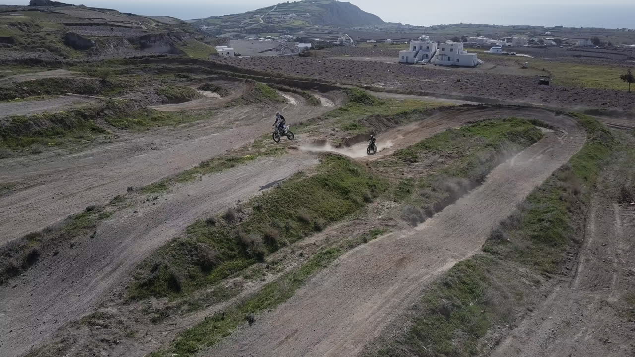 두 명의 모토크로스 라이더가 트랙에서 점프할 때 앞으로 나아가는 드론 샷