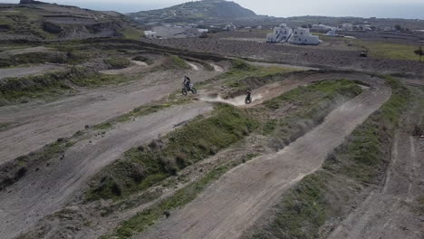 disparo de drones empujando hacia adelante mientras dos pilotos de motocross golpean el salto en la pista