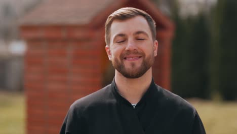 close-up portrait of a young priest taking off his mask and smiling