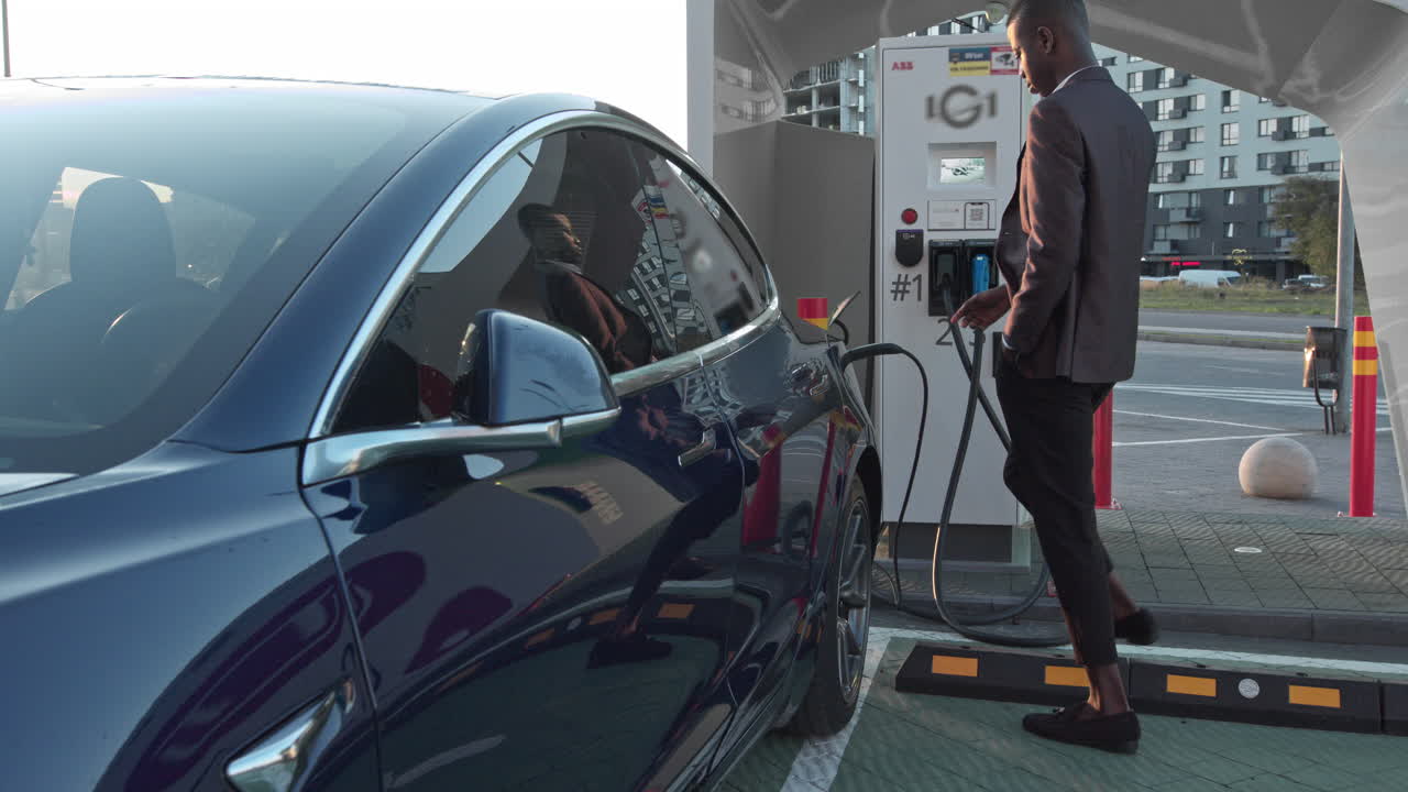 충전소 에서 전기 자동차 를 충전 하는 사람