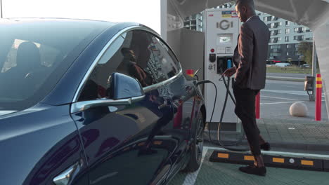 hombre cargando un coche eléctrico en una estación de carga