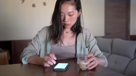 crop asian woman with latte touching screen on smartphone