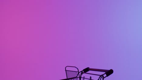 Video-of-shopping-trolley-with-copy-space-over-neon-purple-background