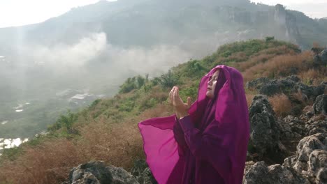 lone moslim woman praying high on rocky mountains close to god in west java