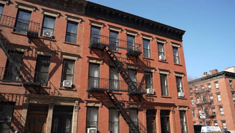 classic brick apartment building with fire escapes in a city on a sunny day