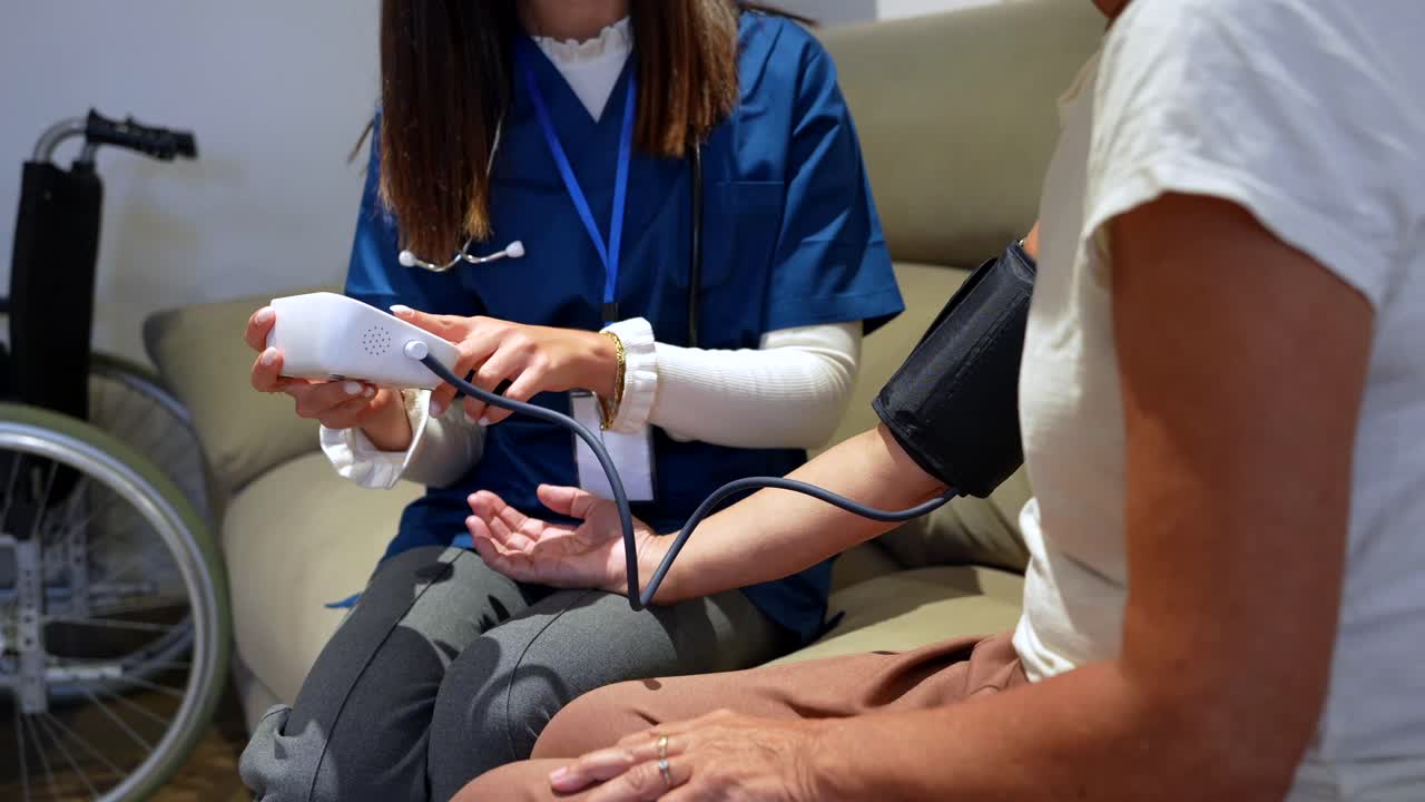 Nurse taking blood pressure of elderly patient at home