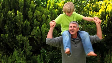 Man-carrying-his-son-on-his-shoulders-in-the-garden