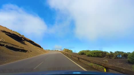 scenic drive in teide national park's curvy roads, surrounded by a desert landscape with a clear blue sky, driver pov, tenerife, canary islands, spain