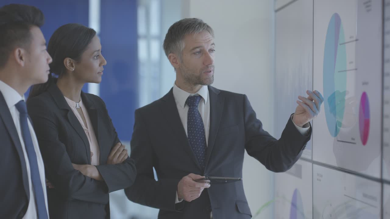 Businessperson meeting in boardroom referencing spreadsheet data on big screen