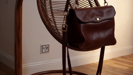 brown leather bag hanging on a rattan chair