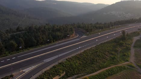 aerial view of a winding highway through a forested mountain landscape at sunrise
