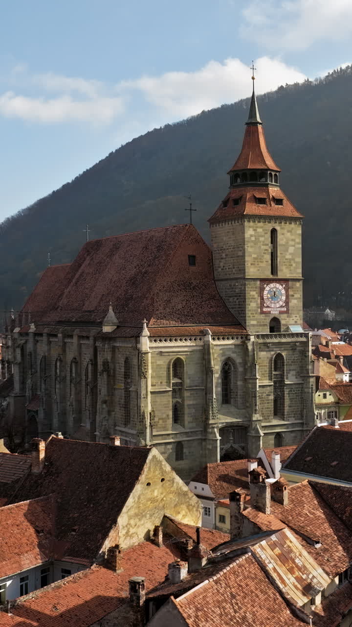 Aerial drone view of The Black Church in the city center of Brasov, Romania surrounded by mountains. Vertical