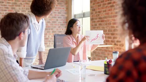 diverse male and female colleagues discussing document in casual meeting, slow motion