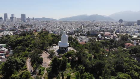 tourist attraction of white buddha statue in park and cityscape of nha trang, beautiful sunny day in vietnam - aerial panoramic