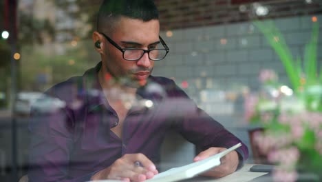 Hispanic-male-entrepreneur-reading-notes-in-cafe