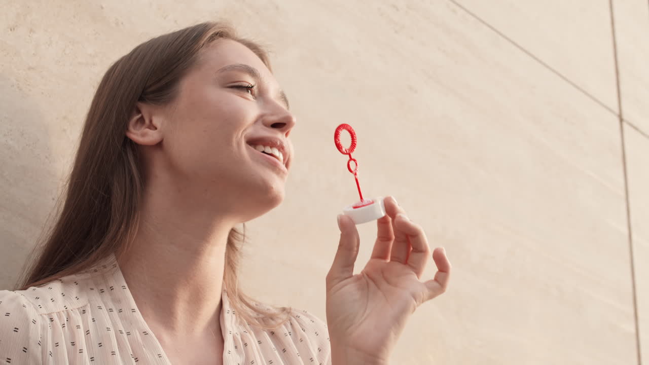 Woman Blowing Soap Bubbles by Wall