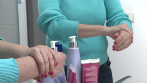 woman applying lotion to her hands in front of a bathroom mirror