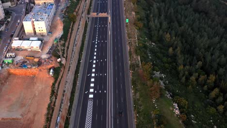 aerial view of a multi-lane highway bordering urban and forest landscapes