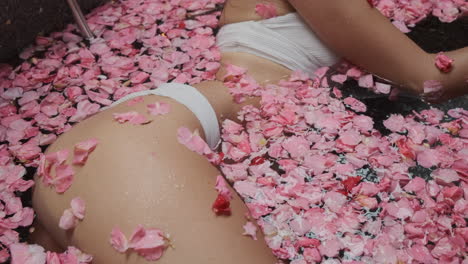 mujer relajándose en un baño de pétalos de rosa