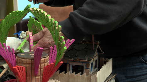 hand of an artisan showing miniature artistic pieces built with wooden springs