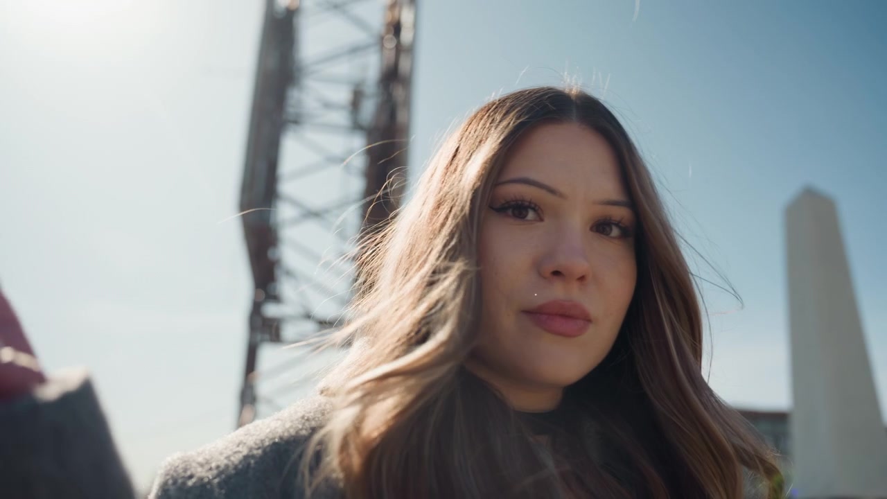 Donna concentrata vicino a un ponte. Posa femminile casual vicino a un ponte con illuminazione delicata e trucco leggero. Donna rilassata con capelli fluenti e gesti delicati in posa vicino a un ponte sotto una delicata retroilluminazione.
