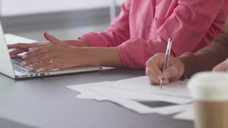 close up of businessman and businesswoman in office working together on laptop and designs