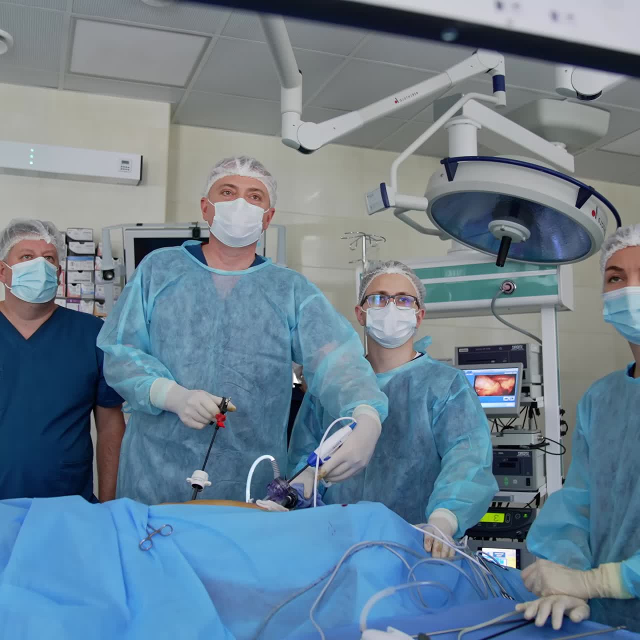 Surgeons applying special medical instruments during operation. Big team of doctors watching the monitors while operating. Modern surgery operation room