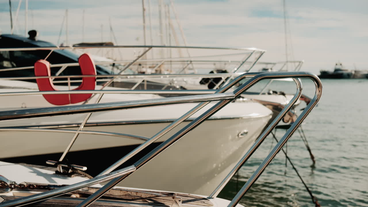 Close up of chrome railing and wooden deck of a luxury yacht docked in a marina under golden light