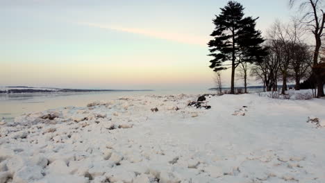 aerial - flying over the frozen shore of the st-lawrence river at sunset