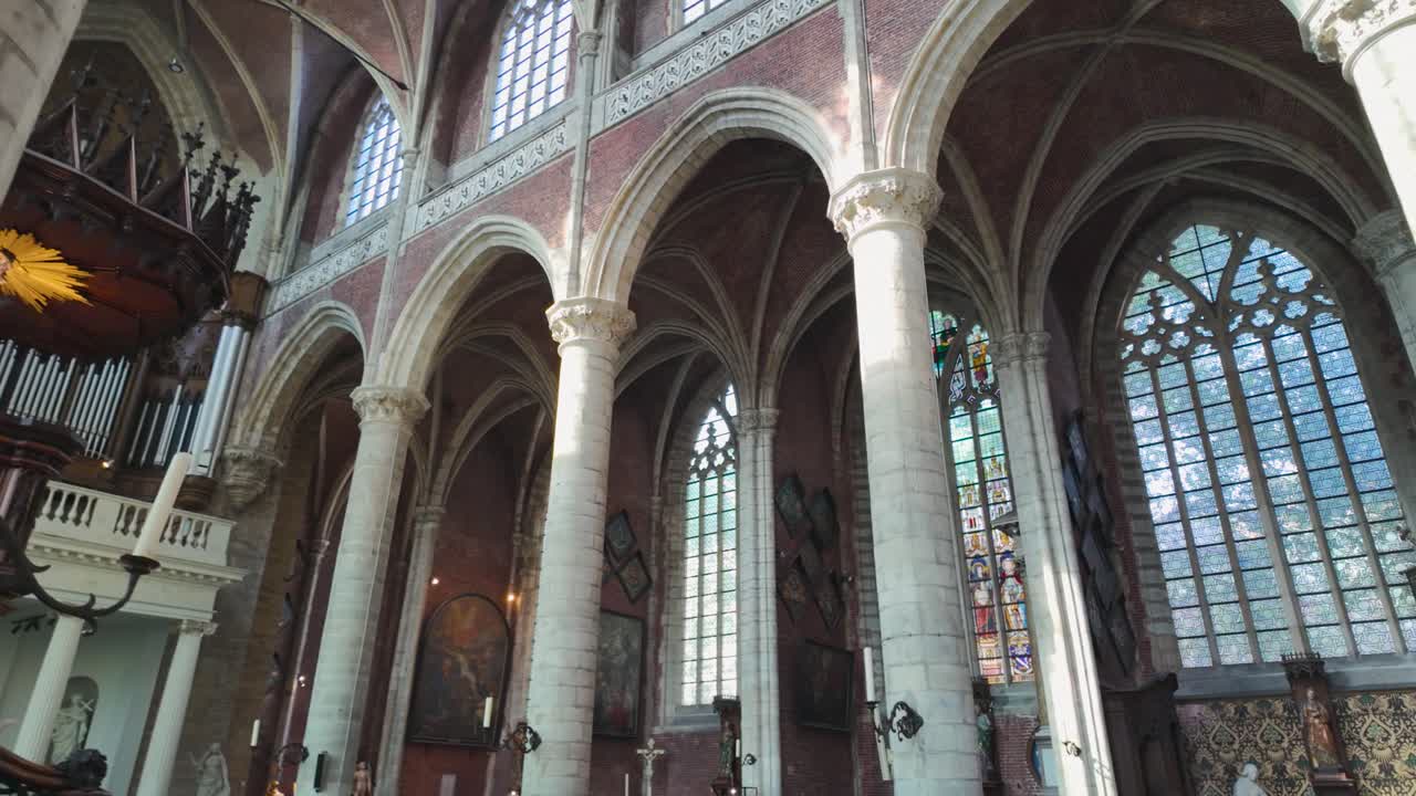 Gothic church interior showcasing high pillars, stained glass windows, and intricate architectural details.