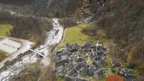 aerial drone top down shot over village houses alongside river maggia in cavergno, district of vallemaggia in the canton of ticino, switzerland on a cloudy day