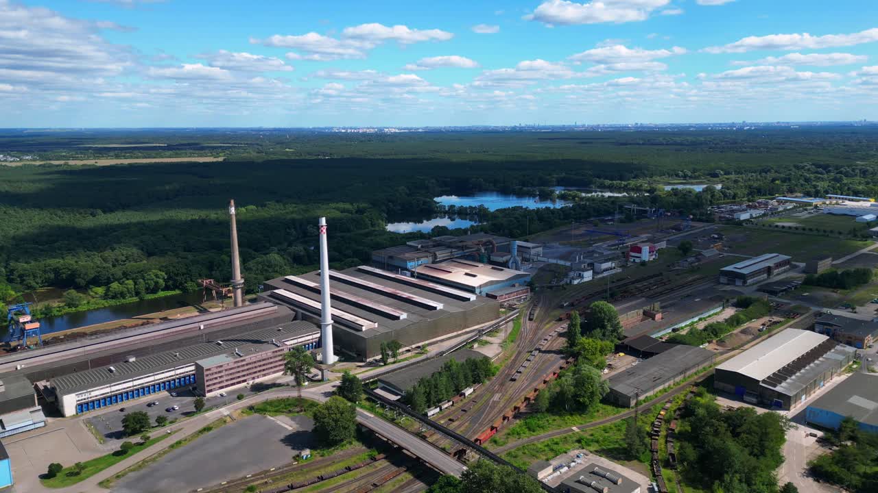 Hennigsdorf Steel Mill showcasing its industrial operations, chimneys, vast railway network, and surrounding landscape. Lovely aerial view flight panorama orbit drone