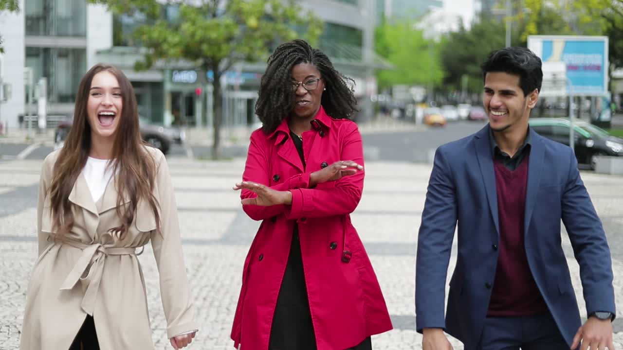 tres jóvenes divirtiéndose por la calle, bailando, riendo