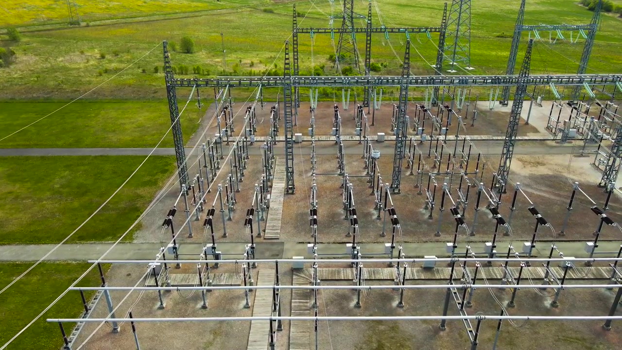 Hochspannungs-Umspannwerk mit Transformatoren und Stromleitungen. Luftaufnahme, die über die Energieverteilungsanlage fliegt.