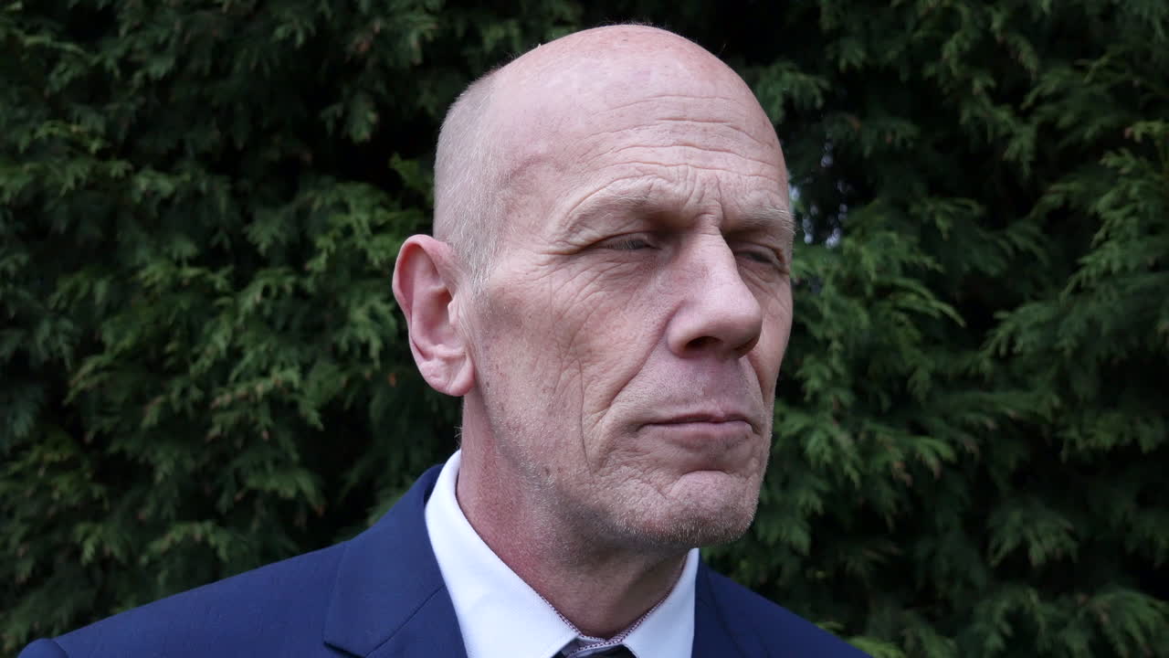 걱정스러운 성숙한 사업가가 숲 속에 서 있는 거리를 바라보며 스트레스를 받고 생각에 잠긴 것처럼 보입니다.