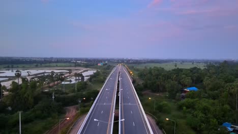 aerial: drone symmetrically flying forward and panning down above a highway early in the morning