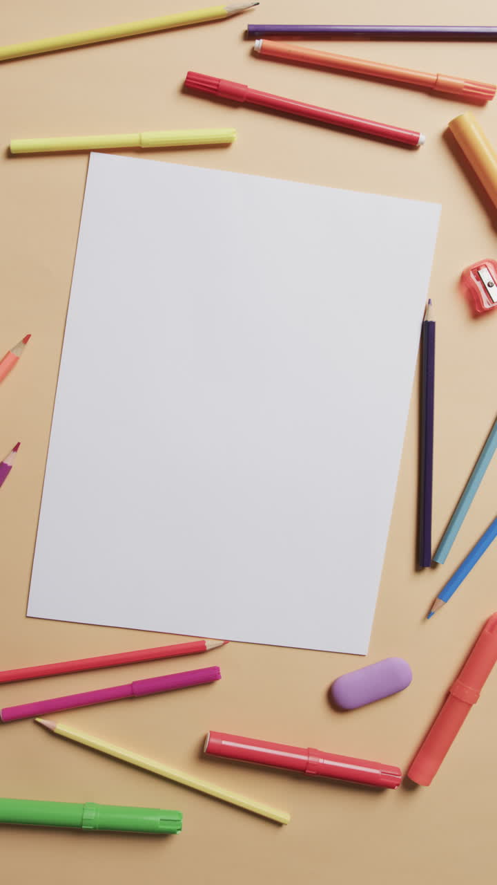 Vertical video of white paper with copy space and pencils on yellow background