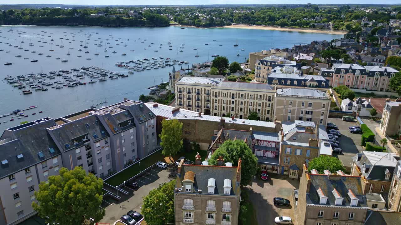 High angle of Dinard marina, boats docked, surrounding cityscape and clear waters visible, aerial dolly establish