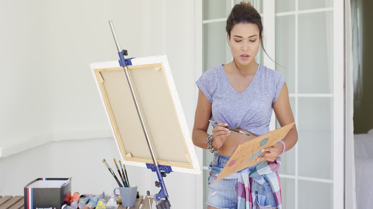 매력적인 여성 예술가가 그녀의 마당에 그림을 그리고 있습니다.