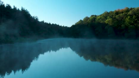 early morning low drone shot over glossy lake with some fog-2