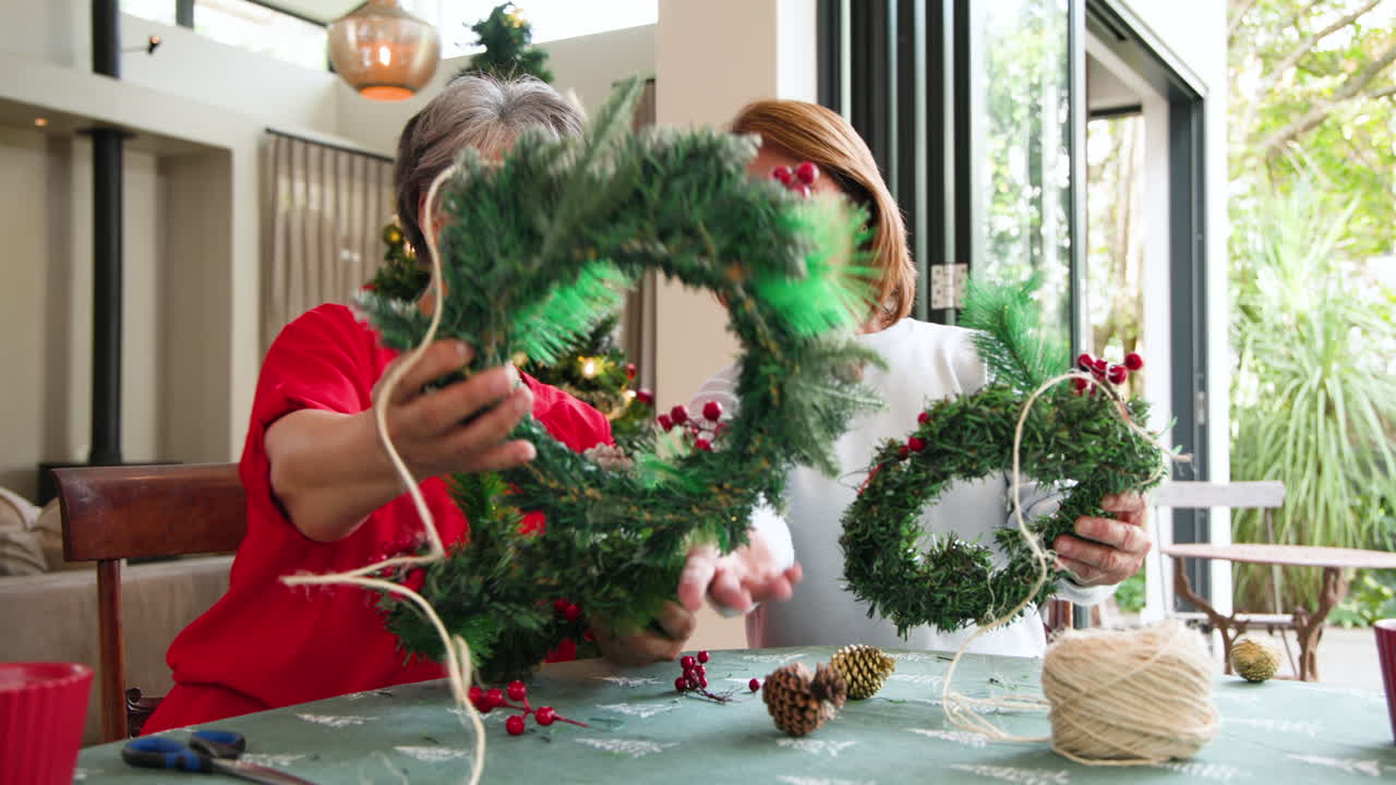Senior women crafting Christmas wreaths together, enjoying holiday spirit at home