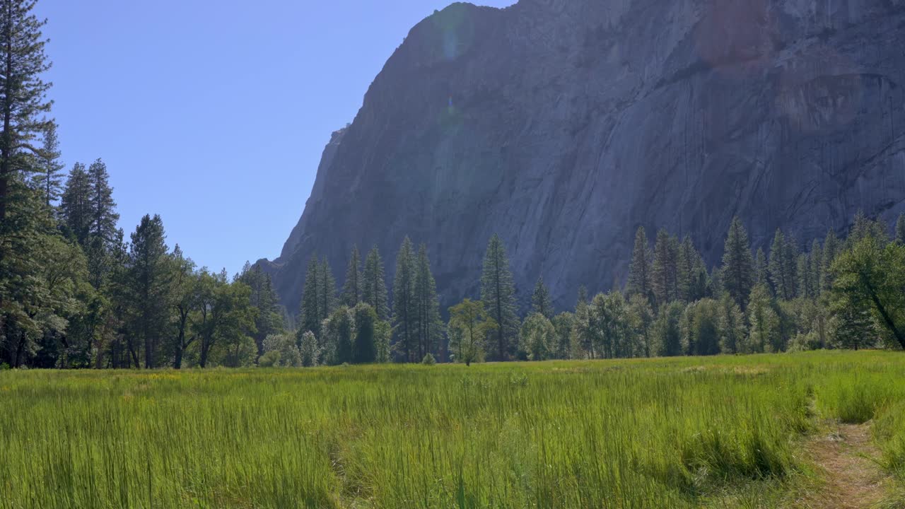 Dramatic granite rock formation rising above the lush green meadows in Yosemite Valley, California