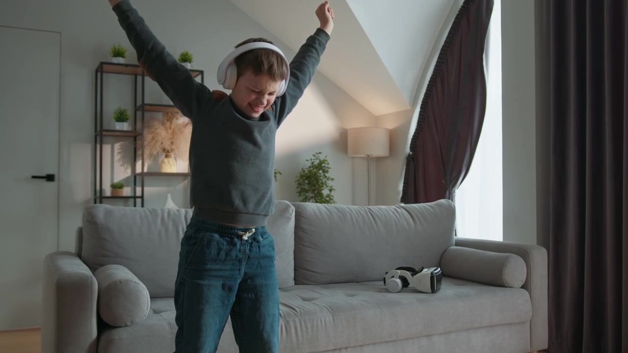 Young boy wearing headphones sits on sofa engrossed in smartphone vr headset nearby the calm scene