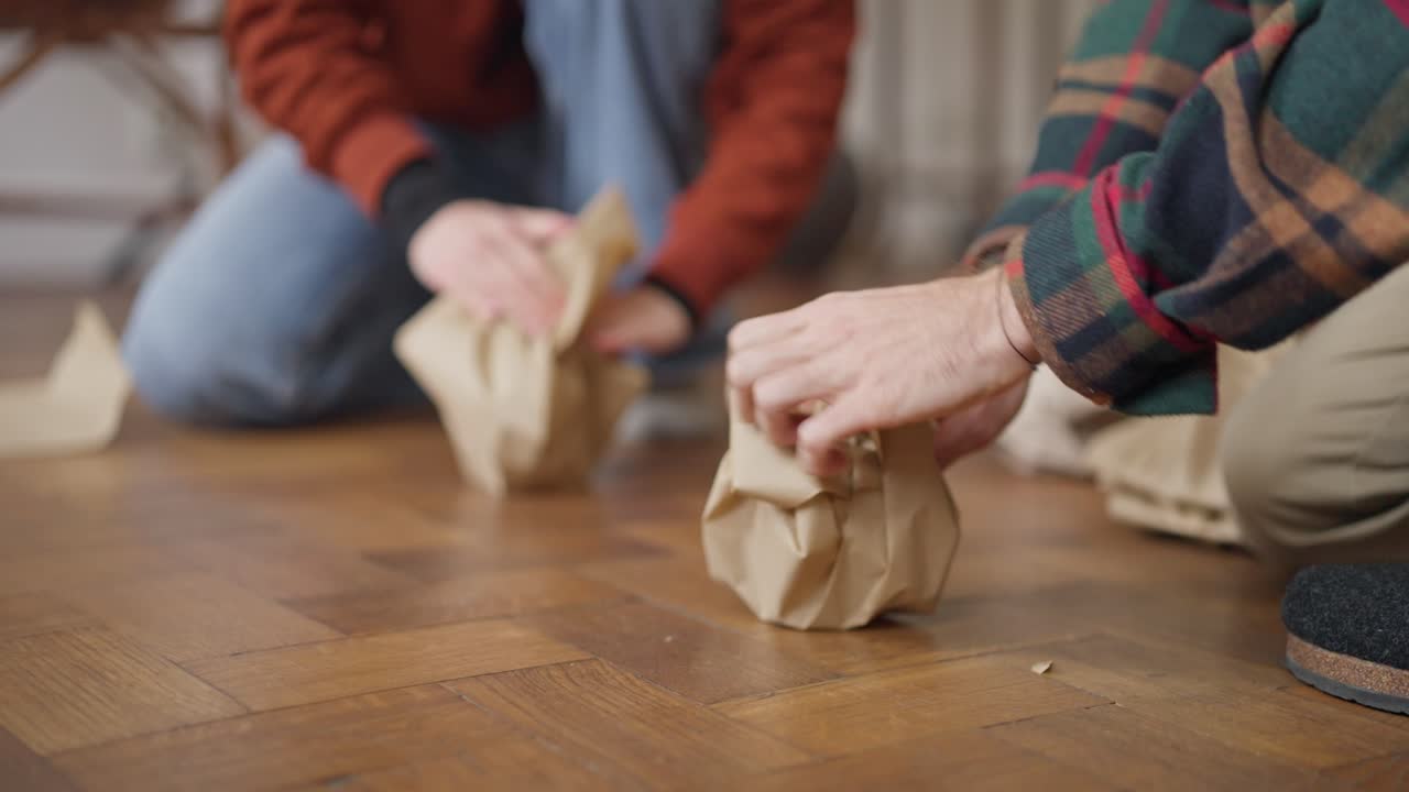 People Packing and Unpacking Items on a Wooden Floor