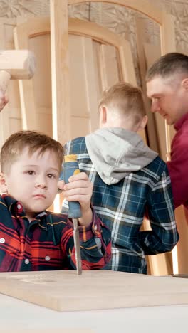 young boy enthusiastically using a chisel while working on woodworking project with family members in a workshop environment, showcasing hands-on learning experience