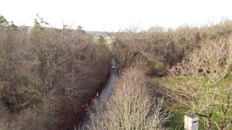 Aerial-of-Car-Driving-on-Empty-Road-in-Forest-on-Cold-Day-in-Winter