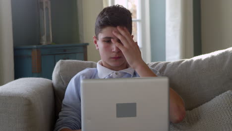 Teenage-Boy-Sitting-On-Sofa-Using-Laptop-At-Home-Shot-On-R3D