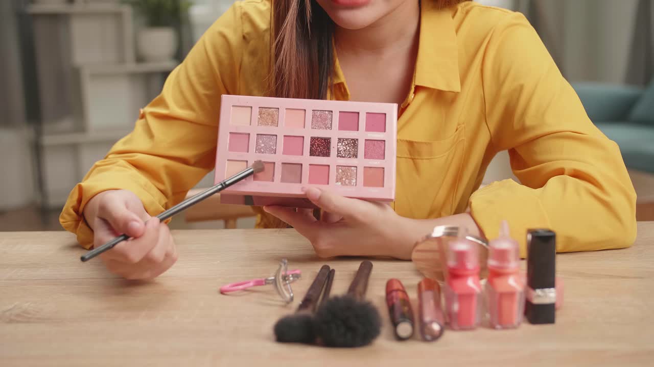 Vlogger Female Showing Eye Shadow Palette. Beauty Blogger Woman Make-Up Routine Tutorial. Influencer Girl Live Streaming Cosmetics Product Review In Home Studio